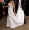 white A-line gown featuring a fitted, subtly ruched bodice with intricate beaded or embroidered detailing at the empire waist.